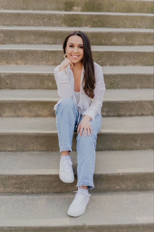 Jacqueline Genova smiling, seated on concrete steps